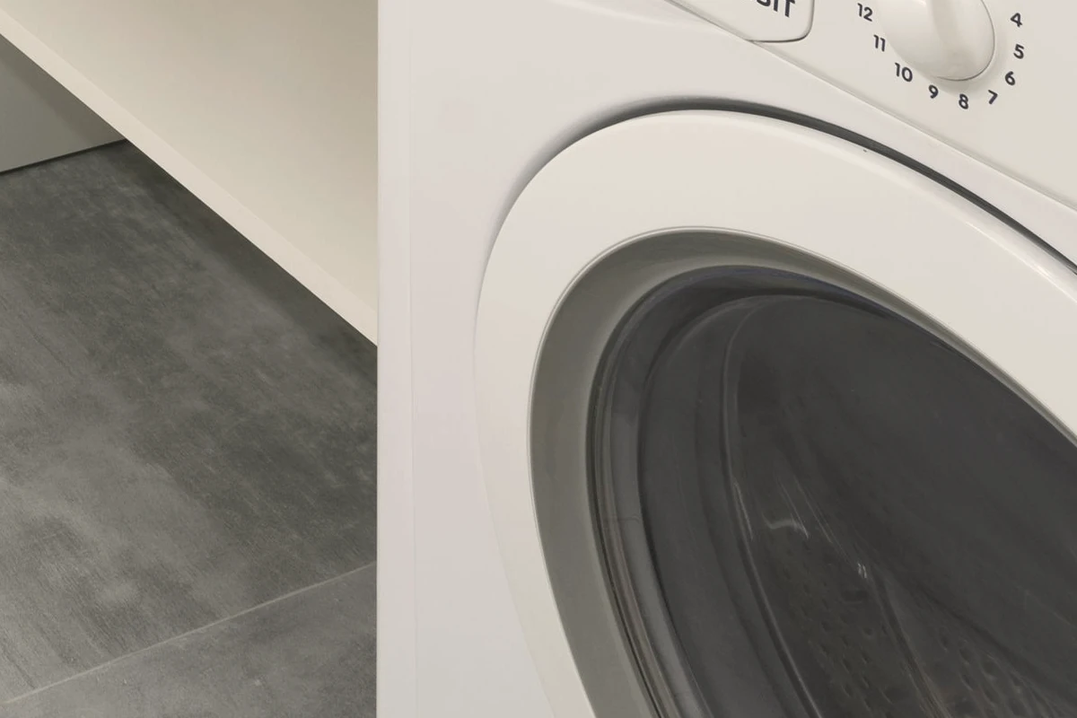 Tezgâh altındaki çamaşır makinesinin kapağı ve solunda lavabo giderinin bağlantı borusu